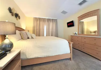 a bedroom with a bed and a dresser and a mirror at Restful 4BR 3BA with BBQ, Heated Pool & SPA in Kissimmee