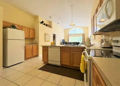 a kitchen with a white refrigerator and wooden cabinets at Restful 4BR 3BA with BBQ, Heated Pool & SPA in Kissimmee