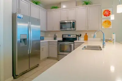 a kitchen with white cabinets and a stainless steel refrigerator at Vacation Home for 8, near Disney and Universal in Kissimmee