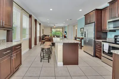 a large kitchen with wooden cabinets and bar stools at 450 Paradise 8BD Villa- Game Room PoolSpa in Orlando