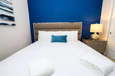 a bedroom with a large white bed with a blue wall at Unforgettable Experience Luxury Vacation Home 7479 in Orlando