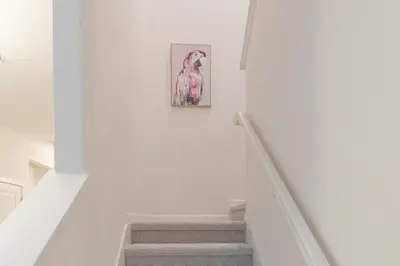 a staircase with a painting of a parrot on the wall at Summer Fun - Waterfront 8BR Home with Private Pool! in Kissimmee