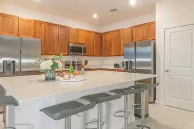 a kitchen with wooden cabinets and a island with bar stools at Summer Fun - Waterfront 8BR Home with Private Pool! in Kissimmee
