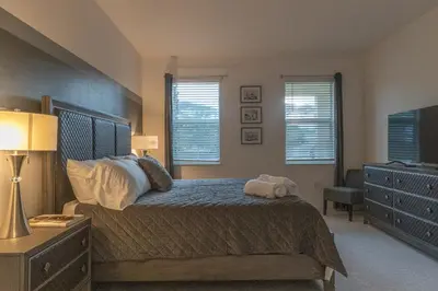 a bedroom with a bed and a dresser and windows at Summer Fun - Waterfront 8BR Home with Private Pool! in Kissimmee