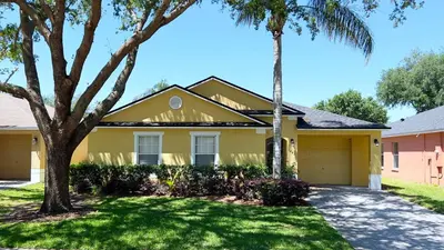 a yellow house with a palm tree and a driveway at Lovely 3-Bedroom Pool Villa-1445SCD in Orlando