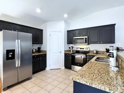 a kitchen with black cabinets and a stainless steel refrigerator at Lovely Lakeside 4-Bed Pool Home at Villa Sol-3125 in Kissimmee