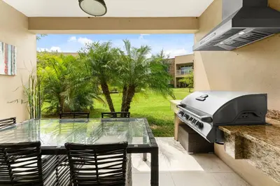 a grill on a patio with a table and chairs at 7648 Magic Village lovely 4suites 8guests 8 min Disney in Orlando