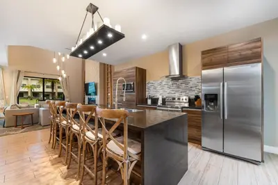 a kitchen with a stainless steel refrigerator and wooden floors at 7458 Magic Village 3suites 8guests jacuzzi 8 min Disney in Orlando