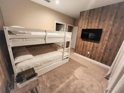 a bedroom with two bunk beds and a flat screen tv at 7458 Magic Village 3suites 8guests jacuzzi 8 min Disney in Orlando