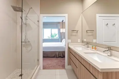 a bathroom with two sinks and a shower with a bed at 7589 Magic Village 8 guests 4 suites BBQ near 192 Disney in Orlando