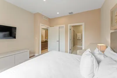 a bedroom with a white bed and a tv at 3212 Magic Village 8 guests lakefront 8 min Disney in Orlando