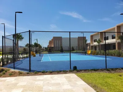 a tennis court behind a chain link fence at 7564 Magic Village 3 suites jacuzzi BBQ 8 min Disney in Orlando