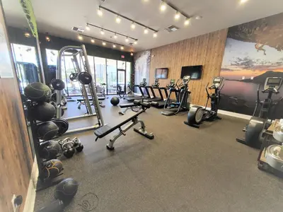 a gym with several treadmills and exercise machines at 3053 Magic Village 3 suites jacuzzi BBQ 6min Disney in Orlando