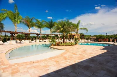a pool at a resort with palm trees and chairs at 3212 WL 8 guests corner 192 near from Disney in Kissimmee