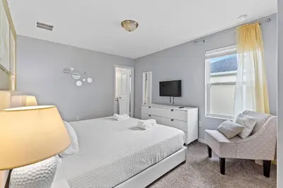 a white bedroom with a bed and a chair at 5129 Tasty renovated 8 guests BBQ near Disney in Kissimmee