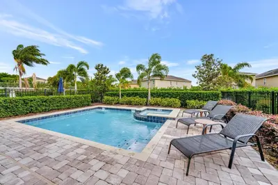 a swimming pool with two chairs and a patio with a swimming pool at Cheerful Home Near Disney With Themed Rooms, Pool Table & Waterpark And Resort Access At Encore Resorts Reunion - 200Mn in Kissimmee