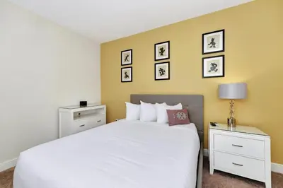 a bedroom with a white bed and some pictures on the wall at Cheerful Home Near Disney With Themed Rooms, Pool Table & Waterpark And Resort Access At Encore Resorts Reunion - 200Mn in Kissimmee