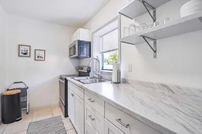 a kitchen with white cabinets and a sink and a window at 6 Mi to Downtown Orlando Quiet Home with Sunroom in Orlando