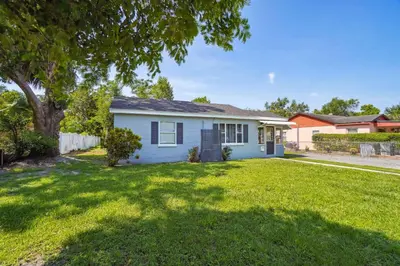 a white house with a tree in a yard at 6 Mi to Downtown Orlando Quiet Home with Sunroom in Orlando