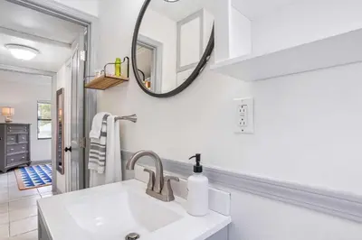 a white bathroom with a sink and a mirror at 6 Mi to Downtown Orlando Quiet Home with Sunroom in Orlando