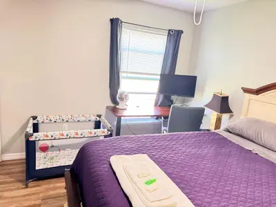 a bedroom with a purple bed and a desk and a window at Near Disney cozy quiet place 2 privet rooms queen bed up to 4 people in Orlando