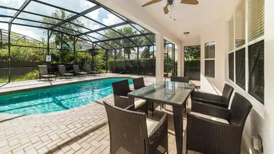 a patio with a table and chairs next to a swimming pool at 2501 Archfeld in Kissimmee