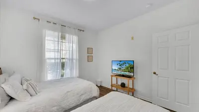 a white bedroom with two beds and a television at 2303 Butterfly Palm #102 in Kissimmee
