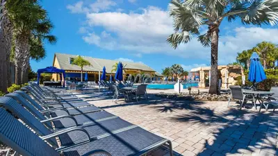 a group of chairs and umbrellas next to a pool at 8967 California Palm in Kissimmee