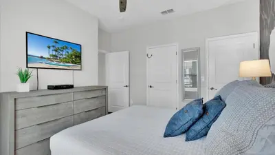 a white bedroom with a bed and a tv on the wall at 3070 Gatsby in Kissimmee