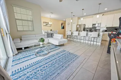 a living room and kitchen with white furniture and a rug at 4837 Lullaby in Kissimmee