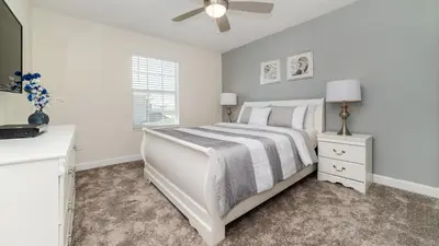 a white bedroom with a bed and a ceiling fan at 4837 Lullaby in Kissimmee