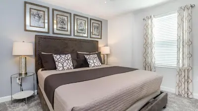 a bedroom with a large bed and two windows at 4543 Narrative in Kissimmee
