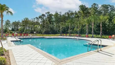 a swimming pool with chairs and trees in the background at 4543 Narrative in Kissimmee