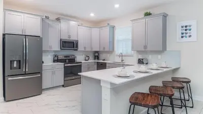 a kitchen with white cabinets and bar stools at 4543 Narrative in Kissimmee