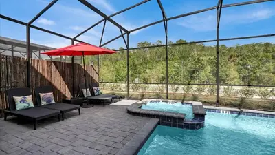 a swimming pool with a red umbrella and some chairs at 2718 Oxymoron in Kissimmee