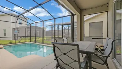 a patio with a table and chairs next to a pool at 4277 Prologue in Kissimmee