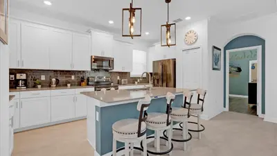 a kitchen with white cabinets and a island with bar stools at 4277 Prologue in Kissimmee