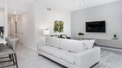 a white living room with a white couch and a tv at 3180 Paradox #303 in Kissimmee