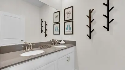 a bathroom with two sinks and three pictures on the wall at 4361 Quote in Kissimmee