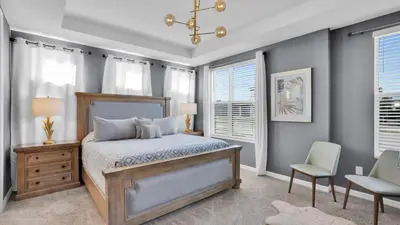 a bedroom with a bed and a chair and windows at 2147 Cooper Bell in Kissimmee