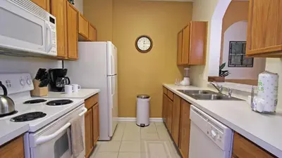 a kitchen with white appliances and a clock on the wall at 7660 Comrow #303 in Kissimmee