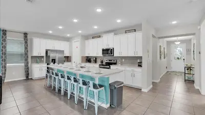 a kitchen with white cabinets and a large island with stools at 1840 Caribbean View in Kissimmee