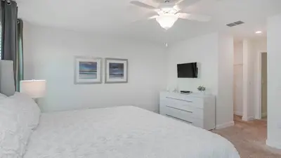 a white bedroom with a bed and a ceiling fan at 4741 Kings Castle C in Kissimmee