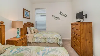 a bedroom with two beds and a dresser with a tv at 7730 Comrow in Kissimmee