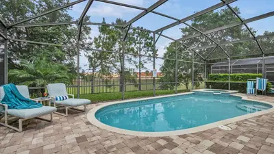 a swimming pool with two chairs and a pergola at 7739 Comrow in Kissimmee