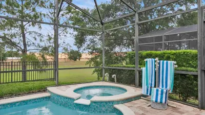 a swimming pool with two blue and white chairs in a pavilion at 7739 Comrow in Kissimmee
