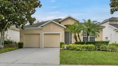 a house with a garage and palm trees at 7739 Comrow in Kissimmee