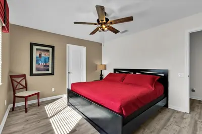 a bedroom with a red bed and a ceiling fan at 7756 Grassendale in Kissimmee