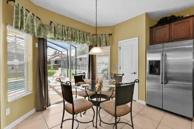 a dining room with a table and a stainless steel refrigerator at 7756 Grassendale in Kissimmee