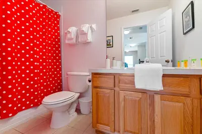 a bathroom with a toilet and a red shower curtain at 2678 Manesty in Kissimmee